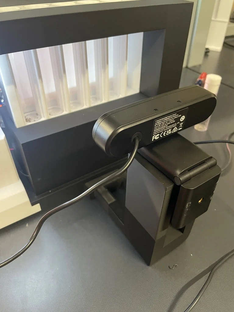 Fixed assay camera facing the backlit vial assembly