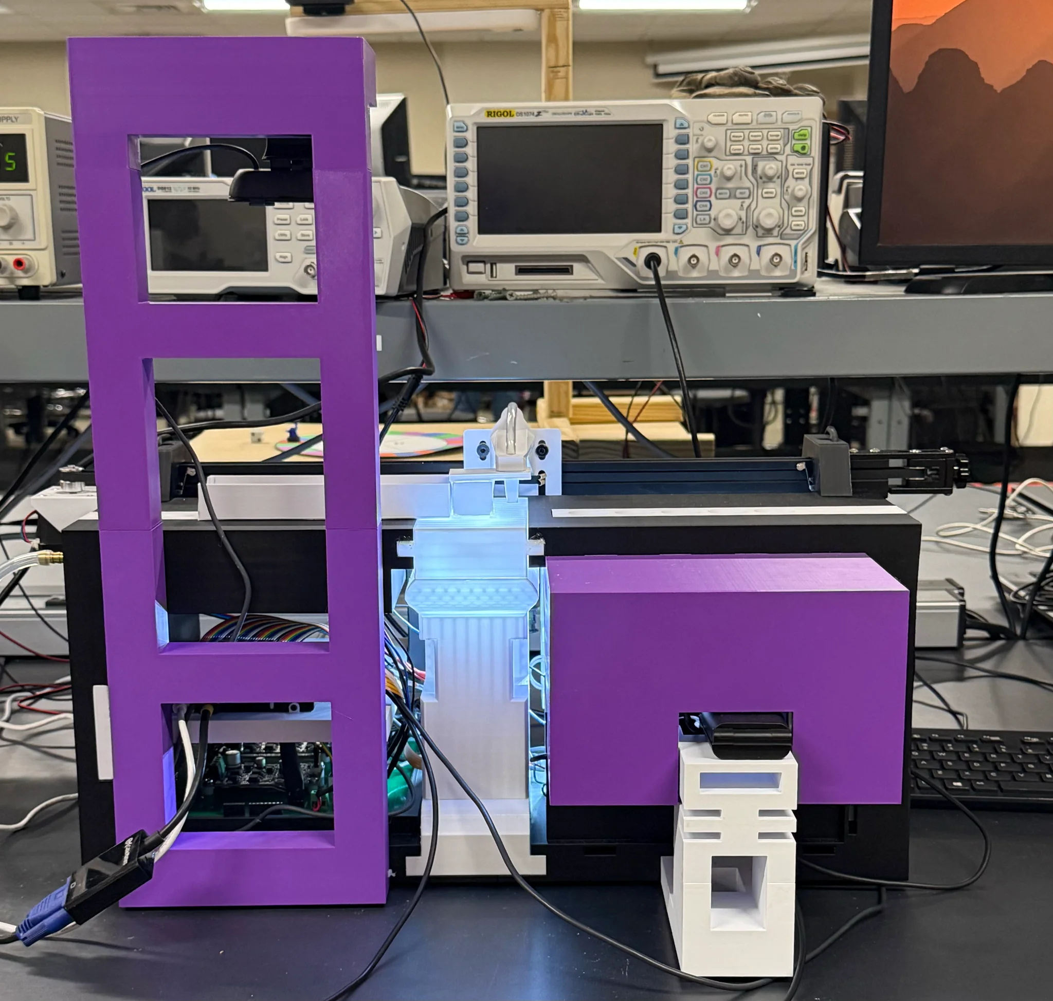 Front view of the complete Drosophila automation prototype with the channel-camera tower, central classification hardware, gantry, and right-side assay enclosure